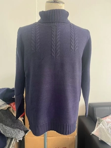 Detail of navy blue cable knit texture and ribbed turtleneck on a warm winter sweater