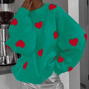 Détail de l'écusson cœur rouge sur un pull en tricot vert avec un col rond classique