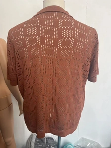 Detailed back view of men's knit shirt showing geometric hollow patterns and ribbed hem