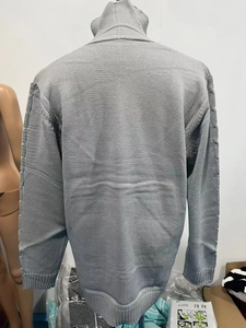 Vista dettagliata del retro del cardigan grigio con maniche a treccia e polsini a costine
