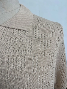 Detailed macro shot of beige hollow knit fabric texture on a short sleeve polo shirt