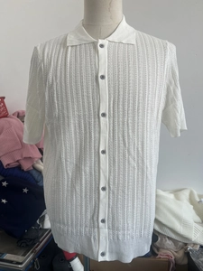 Detail of white knit polo shirt featuring vertical hollow texture and grey buttons