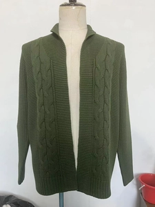 Macro shot of dark green chunky knit cardigan featuring detailed cable braid pattern