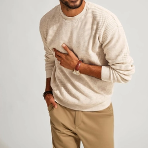 Detailed view of the waffle knit texture and ribbed cuffs on this beige men's sweater