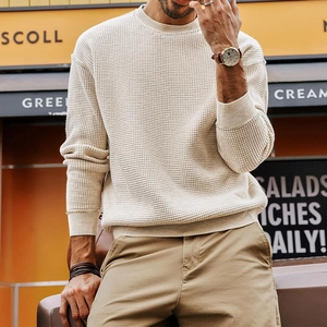 Detail of men's beige waffle knit sweater featuring ribbed crew neck and textured fabric