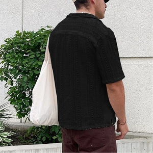 Detail des schwarzen Strickhemdes mit Lochmuster und legerer Schlitz-Handwerkskunst