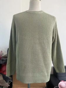 Detail of sage green waffle knit sweater texture and ribbed crew neck design