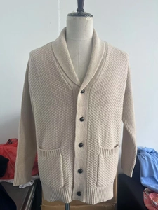 Macro detail of men's shawl collar knit cardigan with heavy texture and button pockets