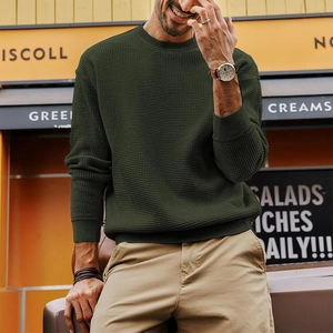 Detail of olive green waffle knit texture and ribbed cuffs on a men's crewneck sweater