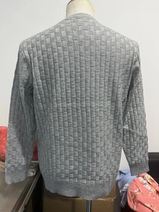 Detail of grey men's knit sweater featuring textured basket-weave pattern and ribbed cuffs