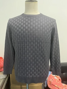 Detail of dark grey crew neck sweater featuring a textured checkerboard knit pattern