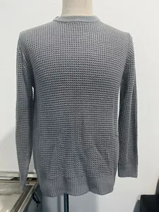 Close-up of the grey waffle knit texture and ribbed crew neck on this men's sweater