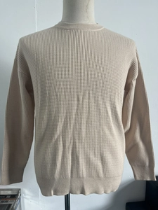 Detailed close-up showing the waffle knit texture and ribbed collar of the beige sweater