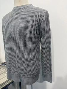 Detail of grey crewneck knit sweater showing waffle texture and ribbed cuffs