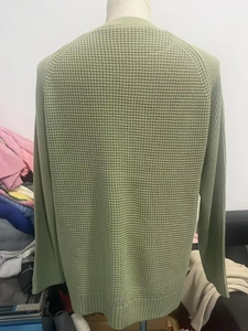 Rear view of light green waffle knit sweater featuring ribbed cuffs and hemline details