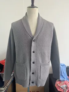 Detail of grey knitted cardigan showing shawl collar, buttons and textured fabric
