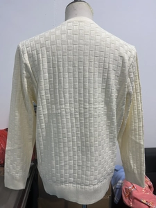 Detail of beige knit sweater showing 3D checkered texture and ribbed hem on back view