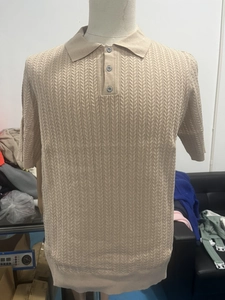Detail eines beigen Herren-Strickpoloshirts mit feinem Zopfmuster und geknöpftem Polokragen