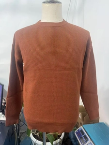 Detail of waffle knit pattern and ribbed cuffs on rust red crewneck sweater