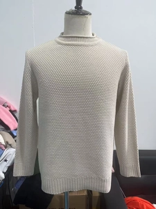 Detailed view of the waffle knit texture and ribbed cuffs on a beige crewneck sweater