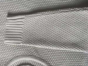 Close-up of waffle weave knit texture and ribbed cuff details on a men's casual sweater