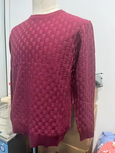 Detailed close-up of dark red crewneck sweater with thick waffle knit texture for men
