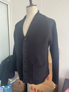 Detail of black men's shawl collar cardigan with textured knit pattern and buttons