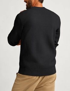 Detail of waffle knit texture and ribbed cuffs on a black crewneck sweater for men