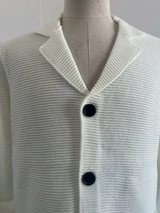 Détail du cardigan en tricot côtelé blanc cassé avec col à revers et boutons contrastés