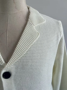 Détail de la maille gaufrée blanche et boutons noirs contrastants sur gilet pour homme