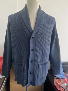 Detail view of dark blue men's knitted cardigan with shawl collar and button pockets