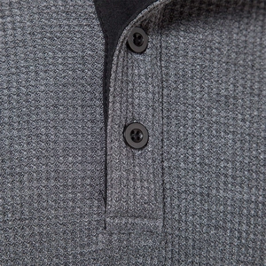 Macro detail of dark grey waffle knit fabric with buttons and black contrast neckline