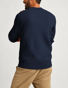 Close-up of dark blue waffle knit texture and ribbed cuffs on men's crewneck sweater