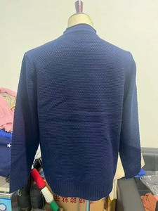 Detail of navy blue waffle knit texture and ribbed hem on a men's round neck sweater