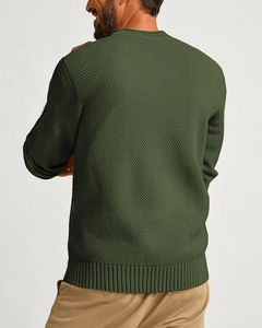 Detail of dark green waffle knit sweater featuring ribbed cuffs and textured fabric