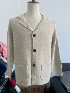 Détail d'un cardigan en maille beige avec col à revers et gros boutons noirs