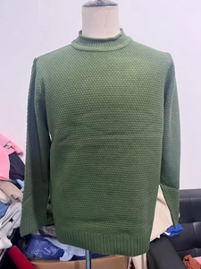 Close-up of dark green waffle knit texture and ribbed cuffs on men's crewneck sweater