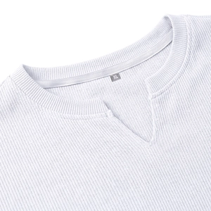 Dettaglio del tessuto bianco a costine con scollo a V e cuciture rifinite di precisione