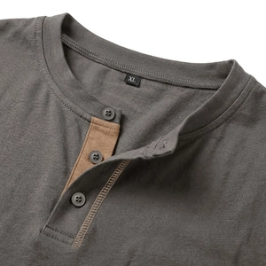 Dettaglio del colletto Henley con bordo a contrasto marrone e bottoni grigi sulla maglia