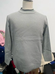 Detailed texture of light grey waffle knit sweater with ribbed cuffs and round neckline