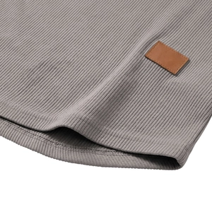 Vista macro del tessuto a maglia a coste grigio con una toppa decorativa in pelle marrone