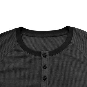 Detail of waffle knit fabric and three-button neckline on charcoal grey men's Henley shirt