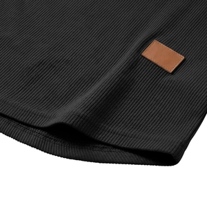 Dettaglio in maglia a coste nere con toppa in pelle marrone e cuciture di precisione