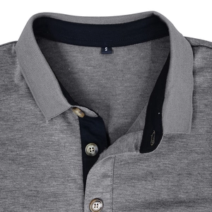 Détail du col d'un polo en tricot gris avec bordure marine et boutons ambrés