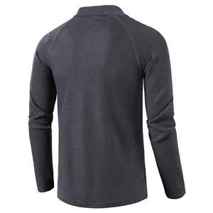 Detail view of charcoal grey waffle knit texture and raglan sleeve design on polo shirt