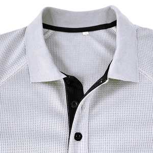 Detailed view of grey waffle knit polo shirt showing contrasting black collar and buttons