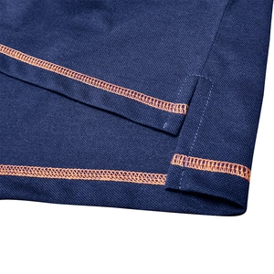 Detailed close-up of dark blue Polo shirt hem with orange contrast stitching and side slit
