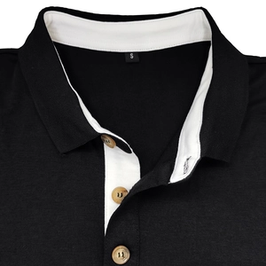 Détail du col polo noir avec contraste blanc et texture des boutons en bois