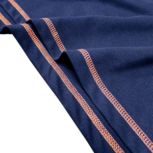 Detailed close-up of dark blue piqué knit fabric with premium orange contrast stitching