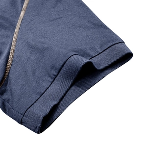 Détail du polo en coton bleu marine avec poignets côtelés et surpiqûres dorées contrastées